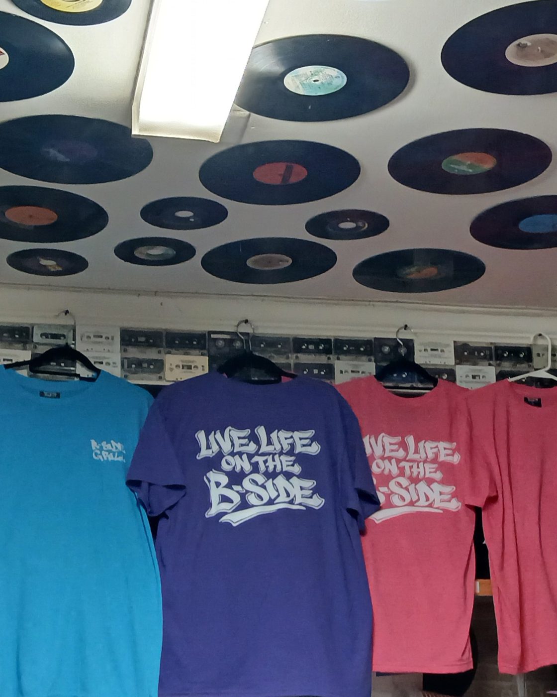 Live Life on the B Side tees hanging under the record ceiling at B-Side Grill