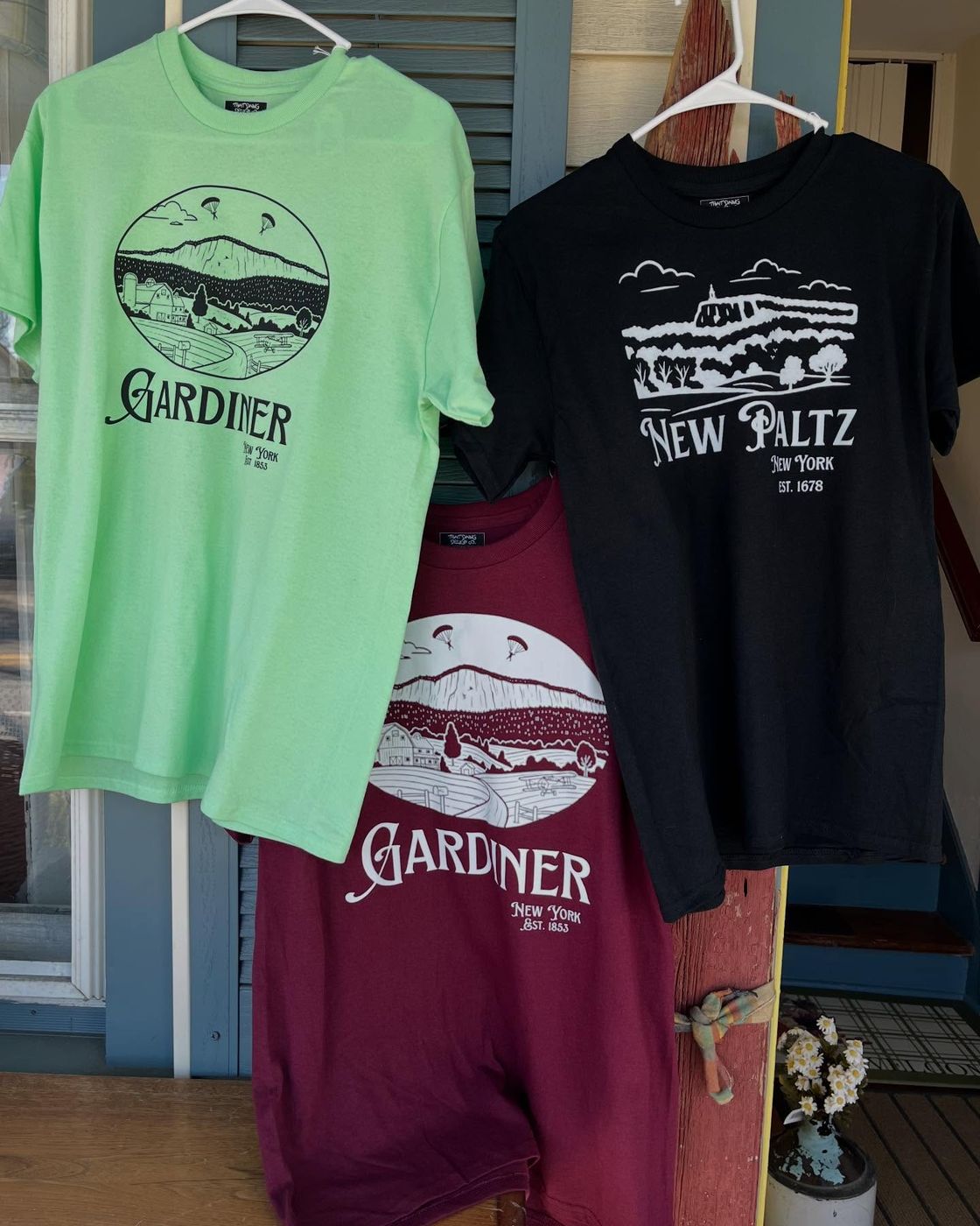 Gardiner tees in mint, black, and maroon hanging on the shop porch